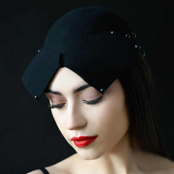 A woman wearing a black funeral fascinator with a large black pearl ornament and bead details on the side.