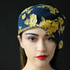 A woman wearing a navy-blue floral print dress hat with yellow flowers.