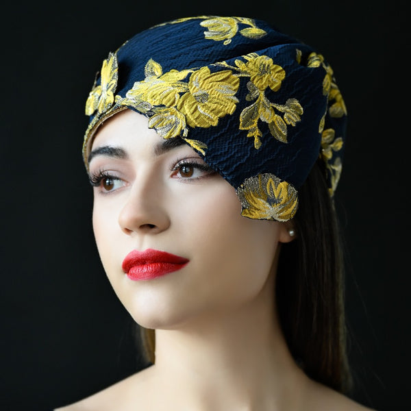 A woman wearing a navy blue floral print dress hat with yellow flowers.