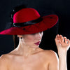 A woman wearing a red felt hat with a black veil detail.