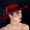 A woman wearing a red felt hat with a black veil detail.